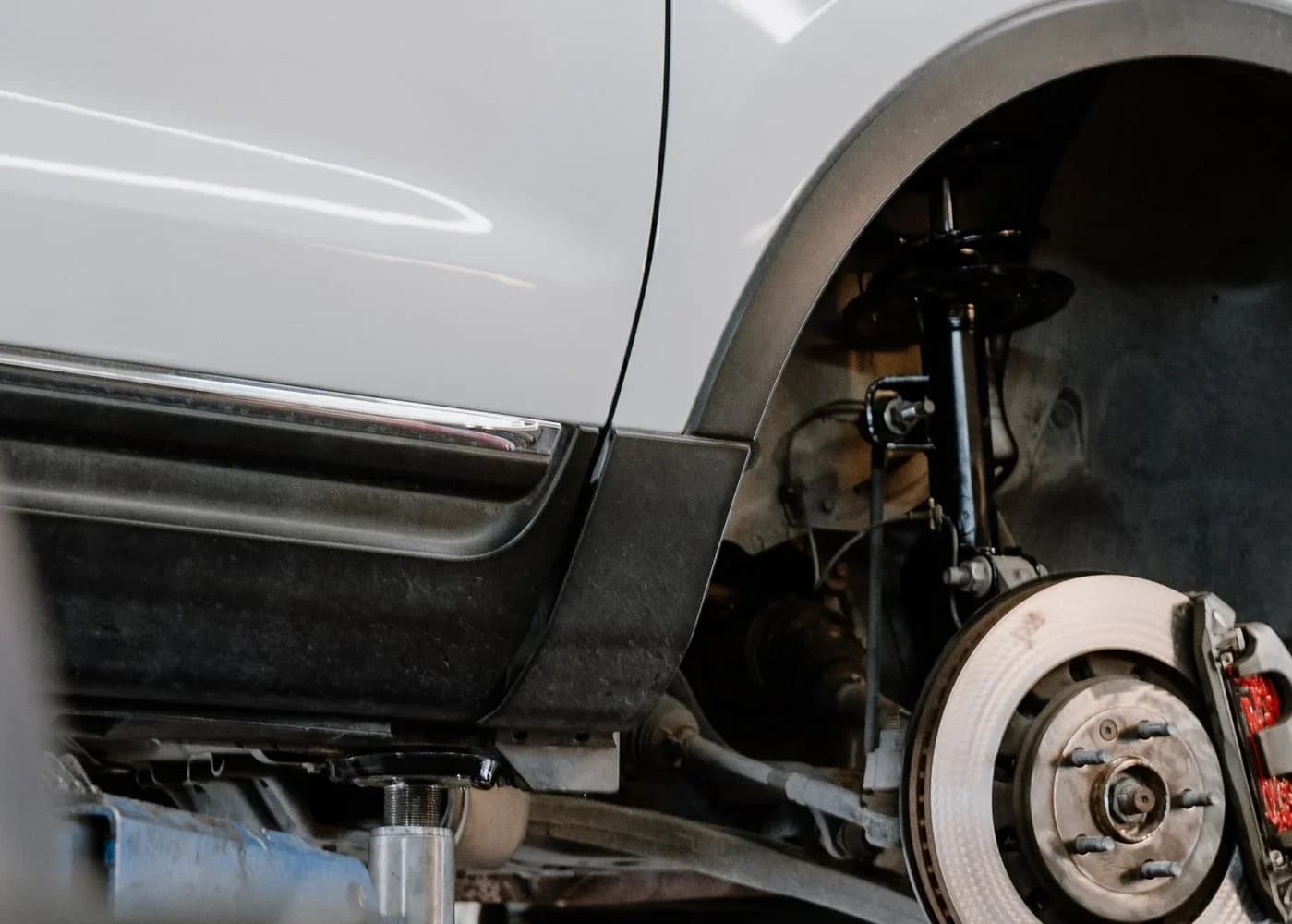 Car on a lift with the wheel off, showing the brake rotor and caliper